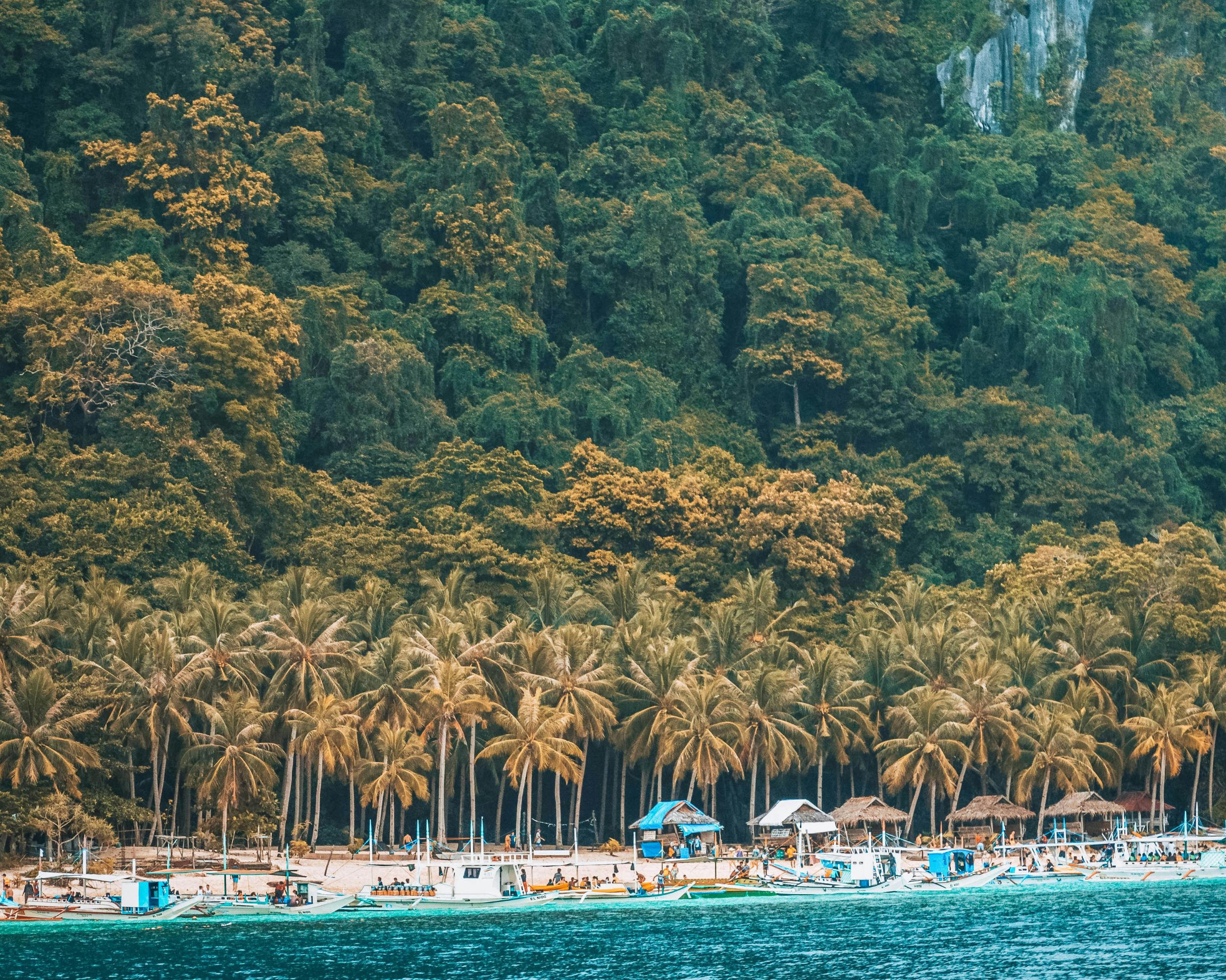 Aerial view of tropical coastline, clear water and traditional outrigger boats