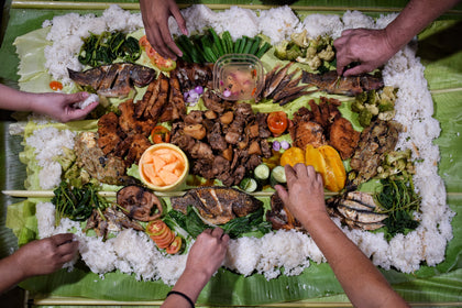 Hands sharing a kamayan meal. Photo: Ej Afable / Wikimedia Commons · CC BY-SA 4.0.