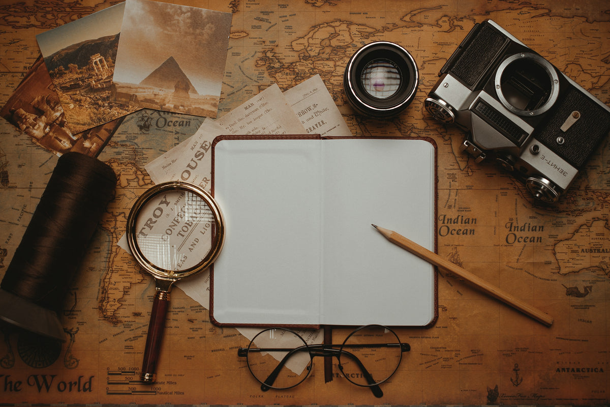 Open notebook, map, camera and magnifying glass used for travel research