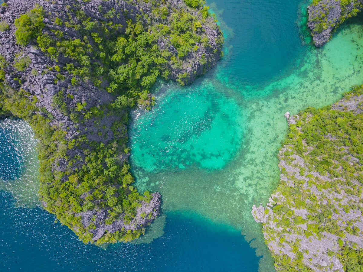 Overhead view of luminous turquoise reef waters and limestone islets in Coron, Palawan; photograph by Florian Delée on Unsplash, https://unsplash.com/photos/MNLneIALcuQ