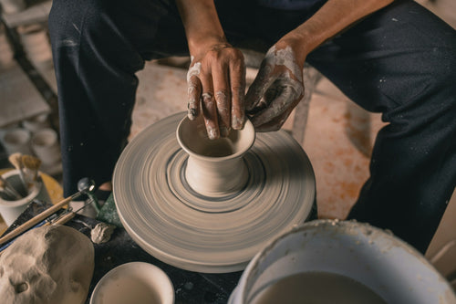 Hands shaping clay on a pottery wheel during a workshop