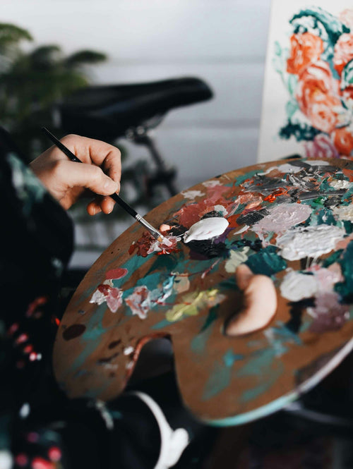 Artist's hand mixing rich pigments on a textured paint palette. Photo: Tabitha Turner / Unsplash. Illustrative editorial image, not a Philippine museum exhibit.