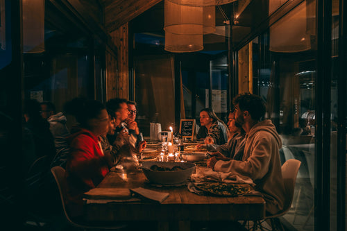 Friends sharing a candlelit dinner around a long table