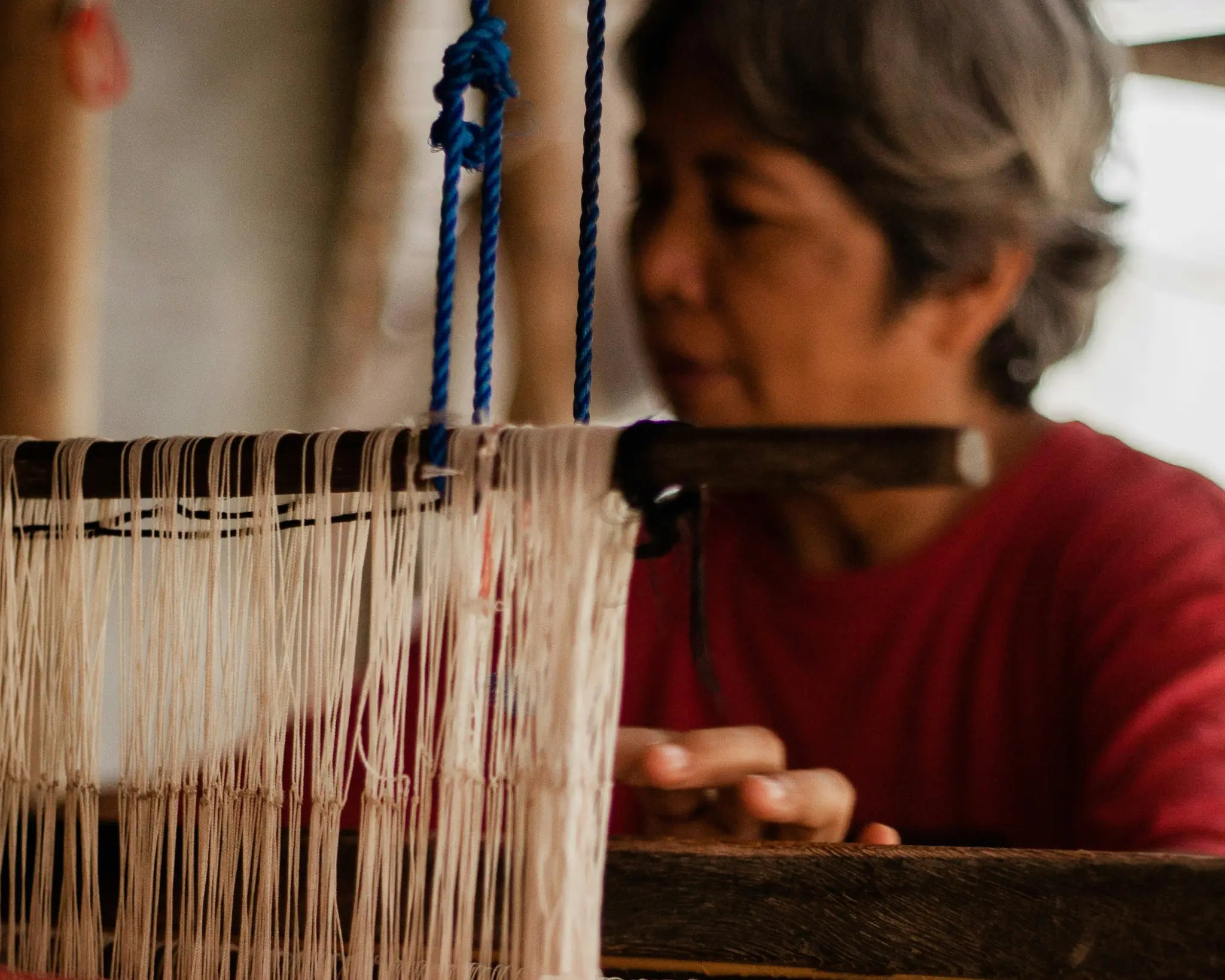 A weaver working attentively at a traditional loom in Argao, Cebu