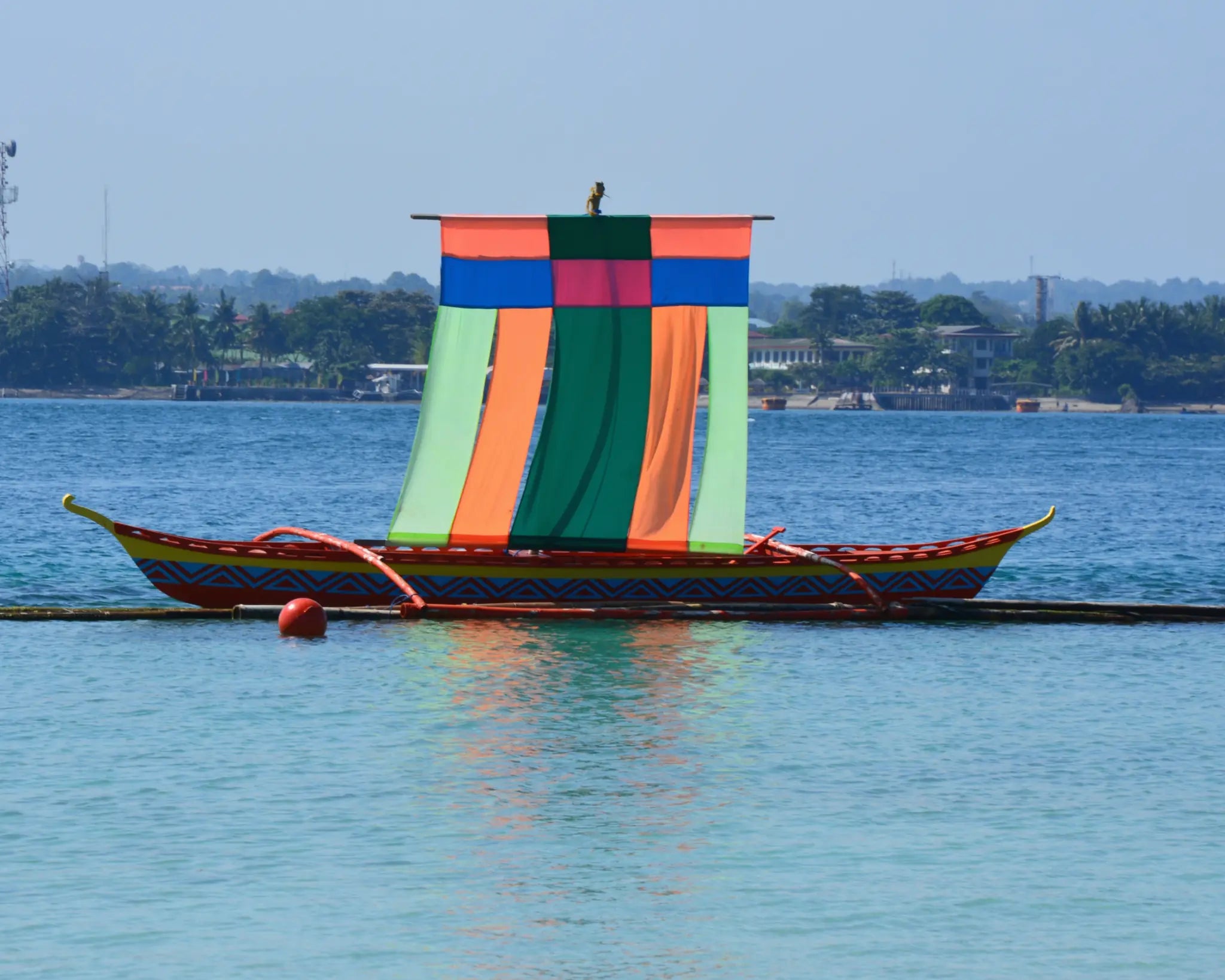 A brightly coloured traditional vinta resting on calm blue water