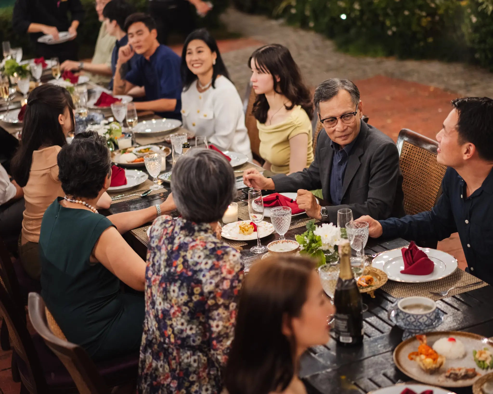 A multigenerational group sharing food and conversation around a long table